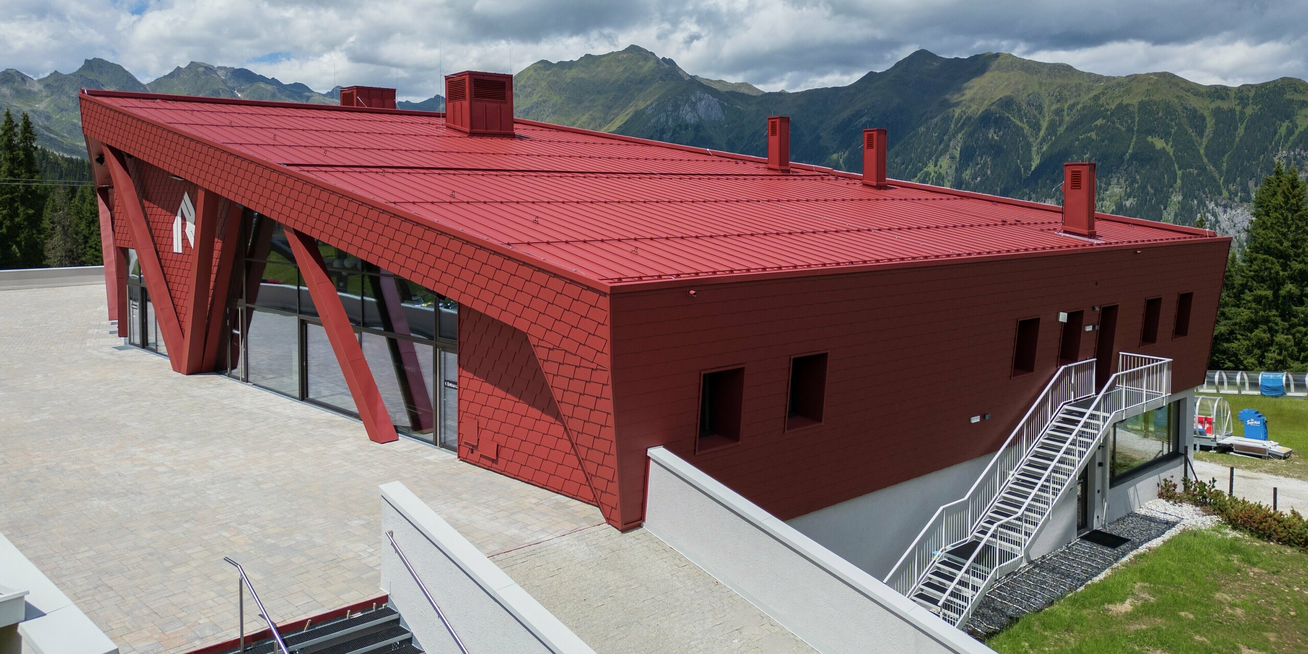 L'architecture impressionnante du Summit Mountain Club de Ratschings se distingue par la remarquable peinture P.10 rouge oxyde qui orne sa toiture et sa façade. Le design moderne et la couleur rouge vif contrastent fortement avec le paysage montagneux verdoyant. On remarque tout particulièrement les grandes baies vitrées et la conception innovante de la toiture, à la fois esthétique, fonctionnelle et robuste – parfaitement adaptée au climat alpin.