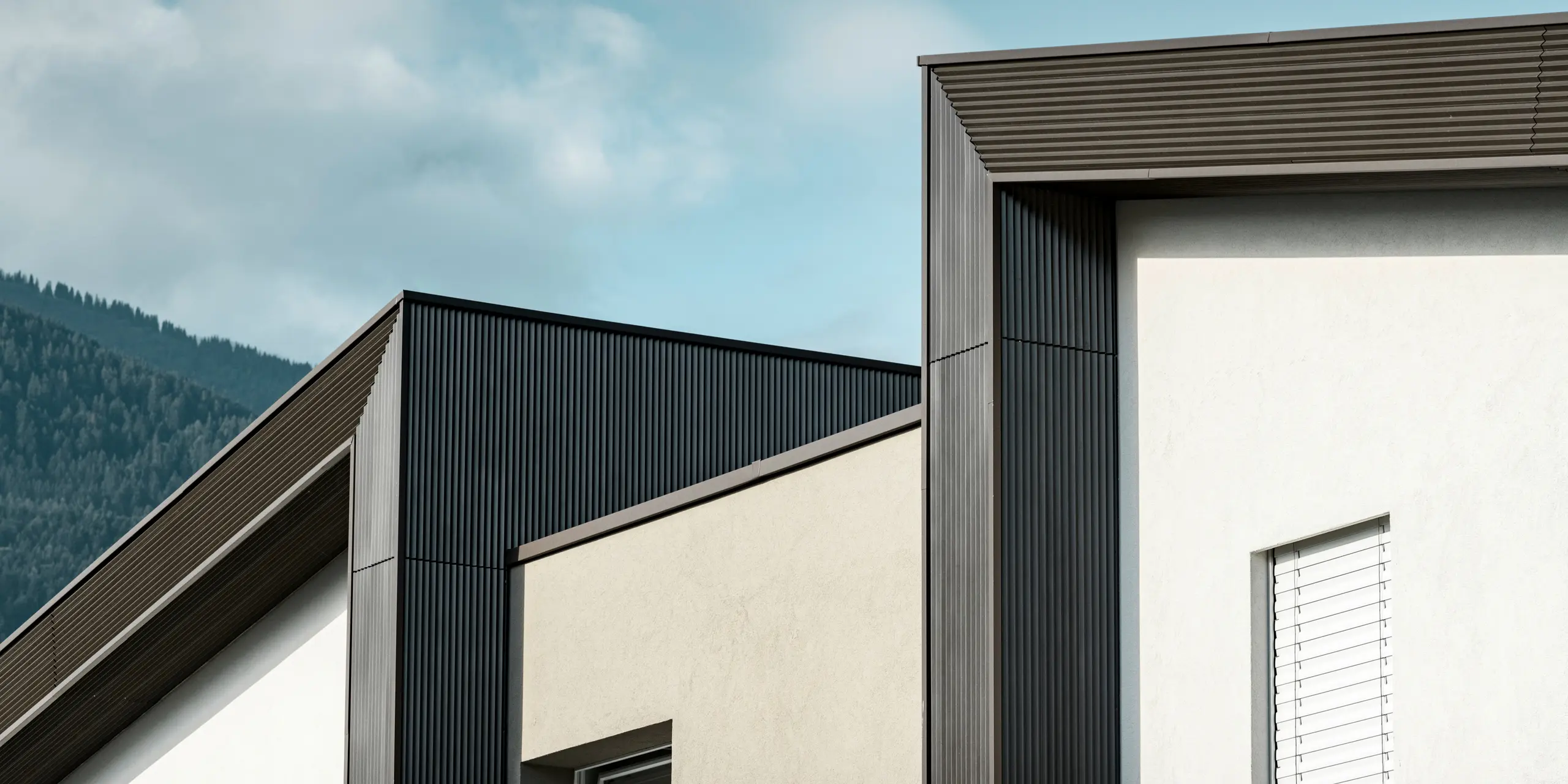 La façade du complexe résidentiel Les Dailles a été largement recouverte de l'impressionnant profil triangle PREFA en bronze. Le toit du bâtiment a été recouvert de PREFALZ en bronze.