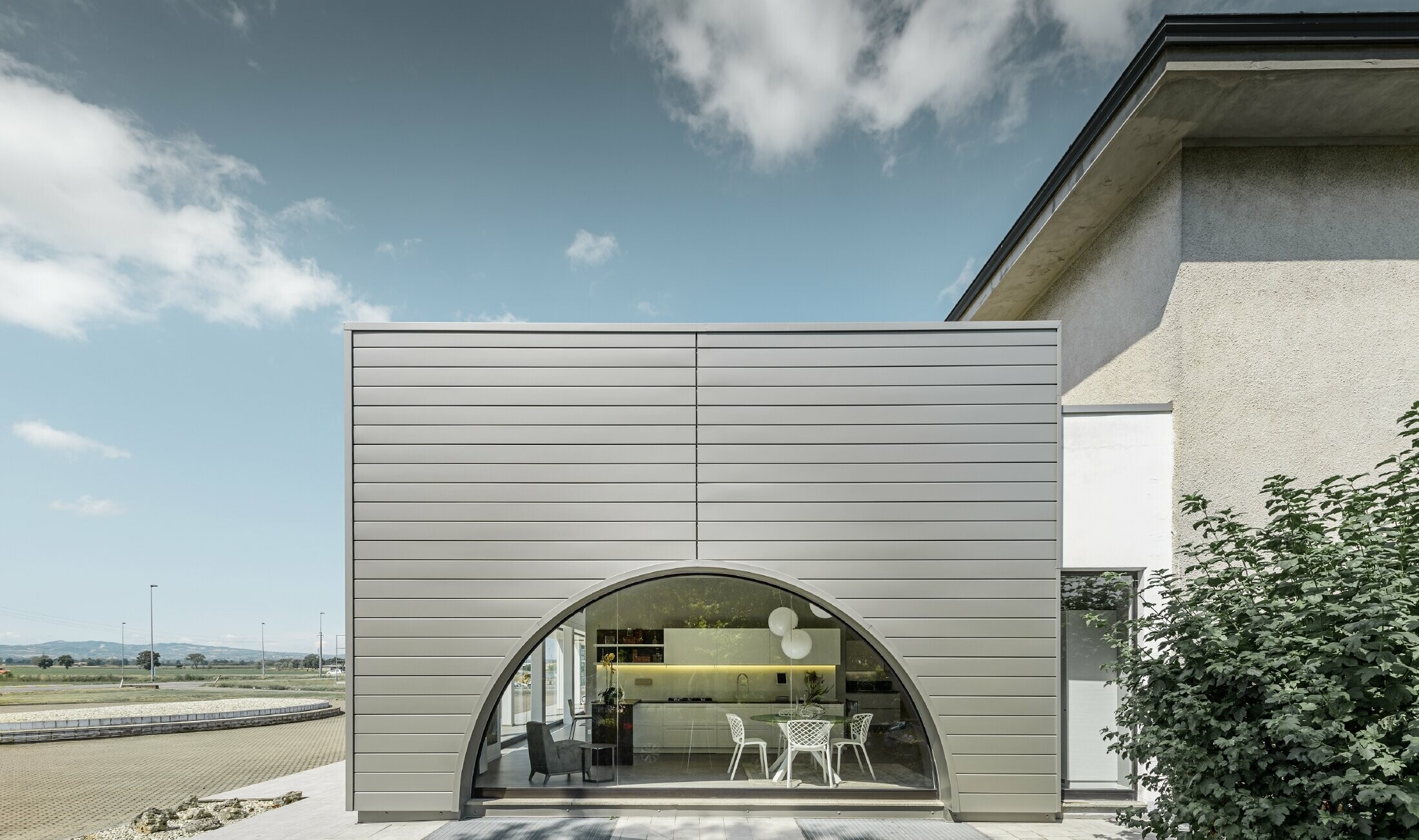 Façade rectiligne avec vitrine courbe ; habillage de façade en aluminium de PREFA avec les Sidings couleur argent fumé