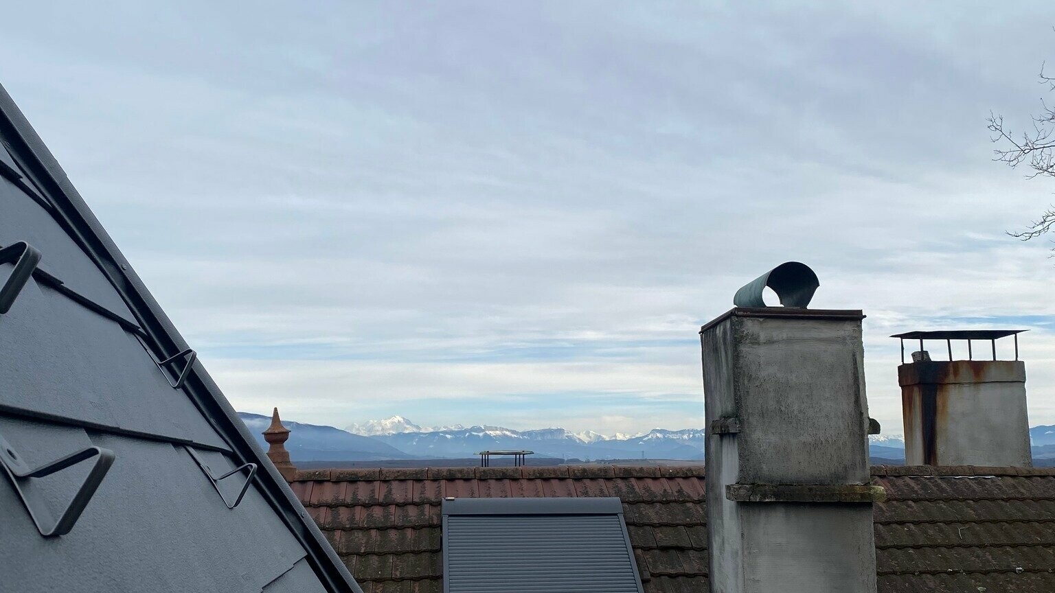 Vue prise depuis le toit en bardeaux PREFA, en arrière-plan on aperçoit les Alpes enneigées 