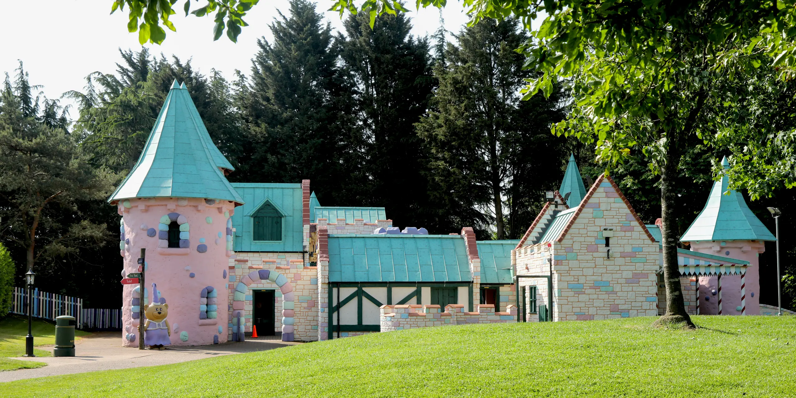 Vue imprenable sur le château féerique de Sundown Adventureland, niché dans un parc verdoyant où des arbres matures forment un écrin naturel. Tours rondes et ludiques, pignons délicats et toitures aux pentes variées créent des jeux de lumière captivants. Les toitures en aluminium PREFALZ, coloris P.10 Vert de gris, apportent une touche d'élégance et soulignent la complexité de l'architecture grâce à leurs joints apparents impeccables. Leur grande malléabilité permet de réaliser facilement les détails les plus complexes, tandis que le système PREFA impressionne par sa durabilité, sa résistance à la corrosion et son étanchéité à toute épreuve.