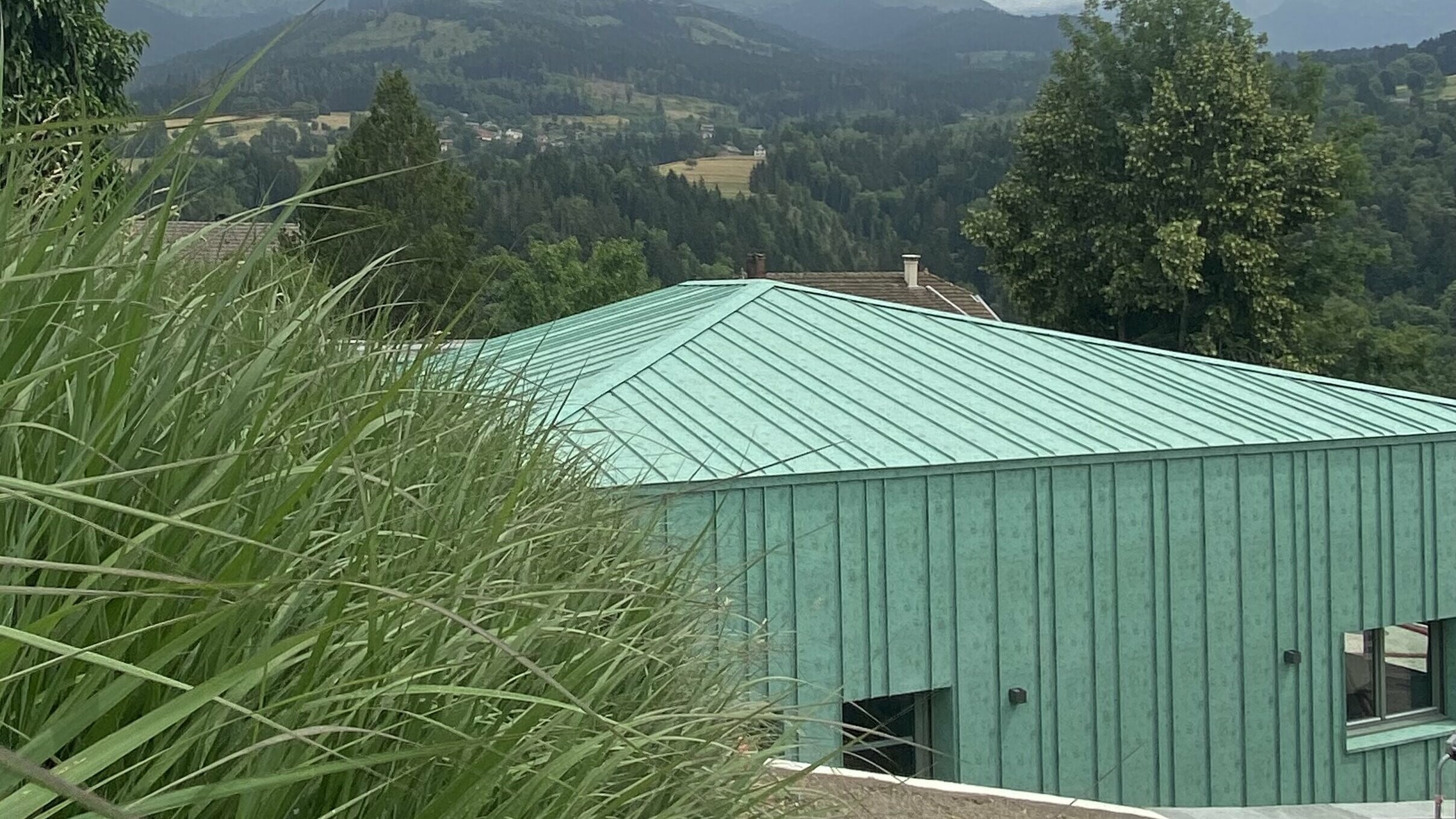 Vue éloignée la nouvelle crèche des Adrets dont la toiture et la façade sont habillées de joint debout Prefalz dans la teinte P.10 vert-de-gris