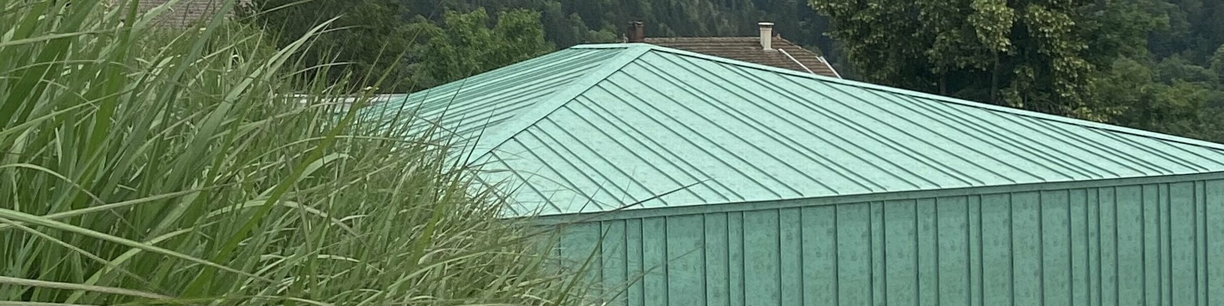 Vue éloignée la nouvelle crèche des Adrets dont la toiture et la façade sont habillées de joint debout Prefalz dans la teinte P.10 vert-de-gris