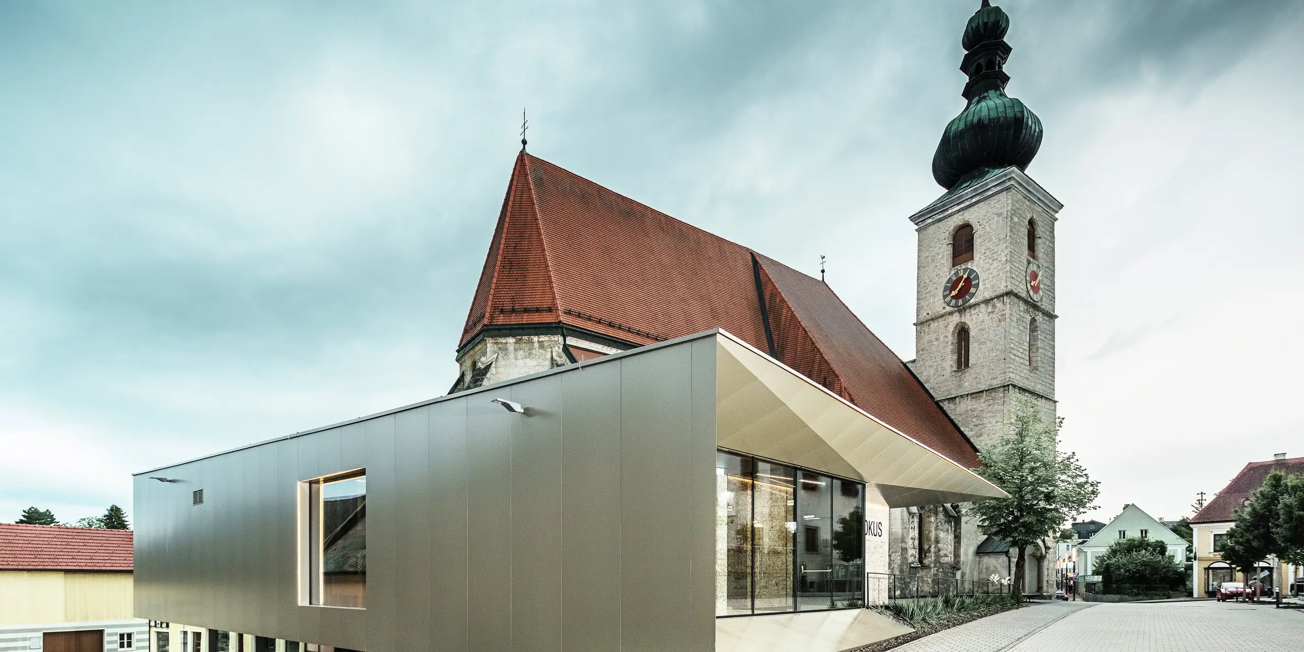 La vue latérale montre l'avant-toit filigrane, réalisé avec des panneaux composites en aluminium PREFA de haute qualité. La finition précise confère un aspect moderne aux lignes épurées et souligne le lien architectural entre l'ancien et le nouveau.
