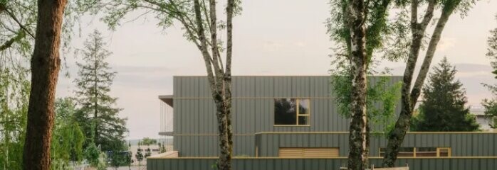Vue éloignée du collège Maryse Bastié dont la façade a été entièrement rénové avec PREFA. On aperçoit la nature et les arbres en premier plan.