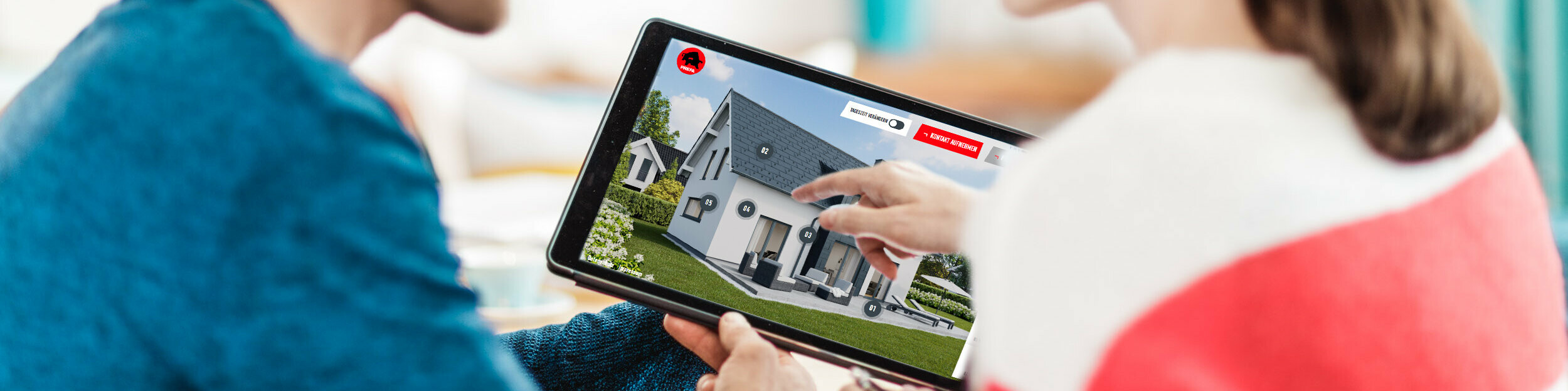 Un couple est assis à la table et regarde sur une tablette la représentation numérique d'une maison avec toit, façade et éléments photovoltaïques en aluminium – dans le contexte du Conseils d’experts PREFA pour toitures, façades et solutions solaires sur bâti neuf ou en rénovation.