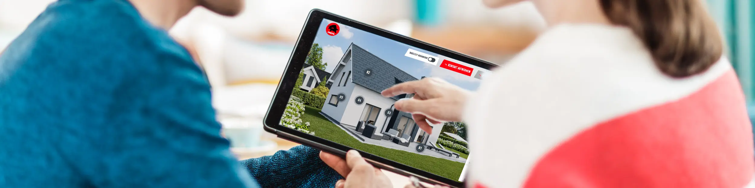 Un couple est assis à la table et regarde sur une tablette la représentation numérique d'une maison avec toit, façade et éléments photovoltaïques en aluminium – dans le contexte du Conseils d’experts PREFA pour toitures, façades et solutions solaires sur bâti neuf ou en rénovation.