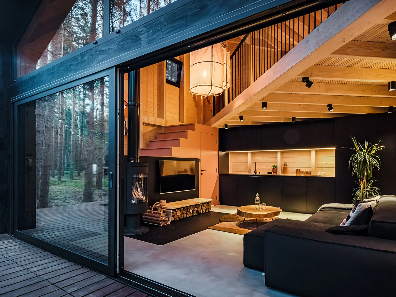 Vue latérale d'une maison de vacances avec un toit en PREFALZ en pente. La nature environnante se reflète dans la zone vitrée.