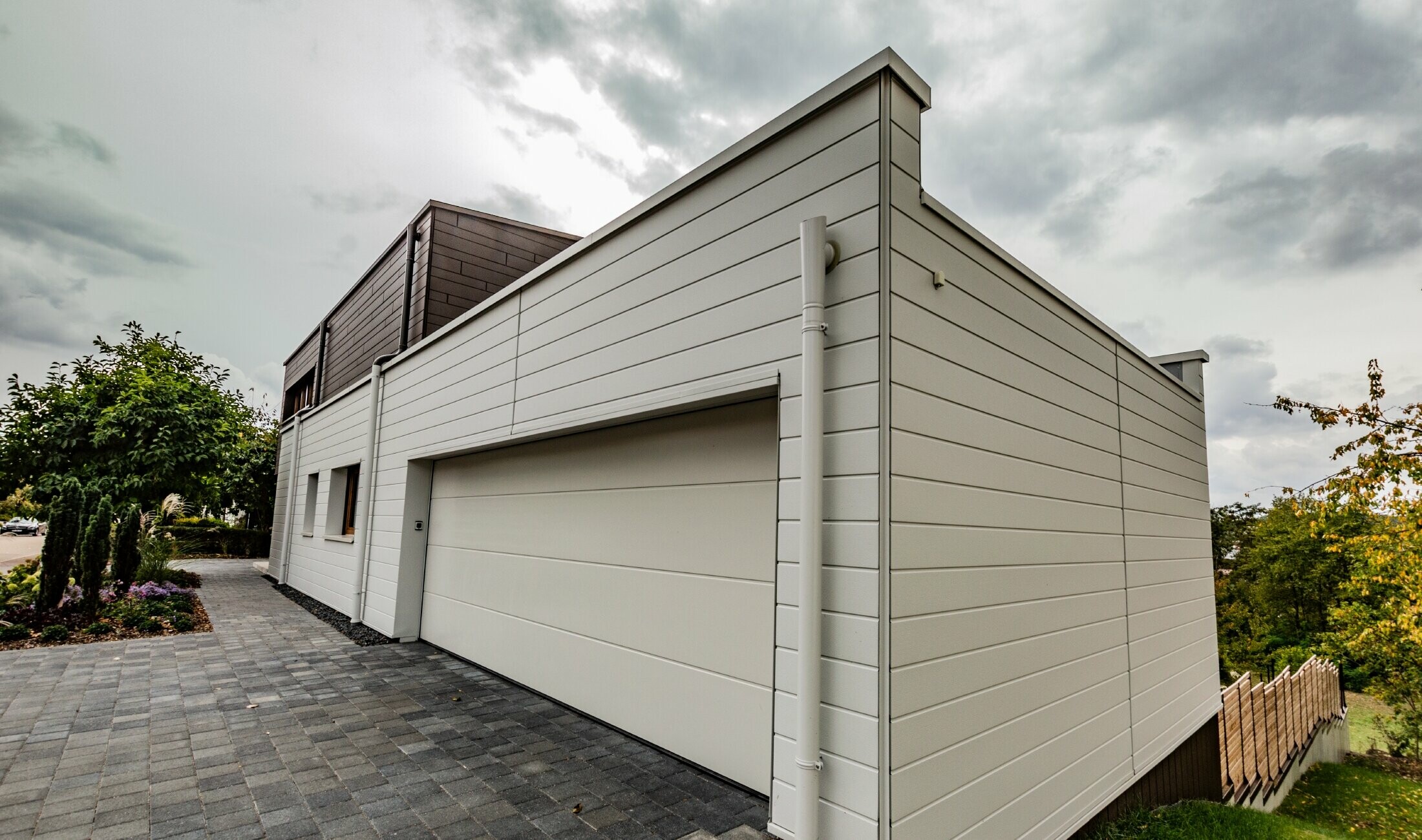 Habillage de garage avec le Siding PREFA en blanc posé à l’horizontale avec l’embranchement d’évacuation PREFA.