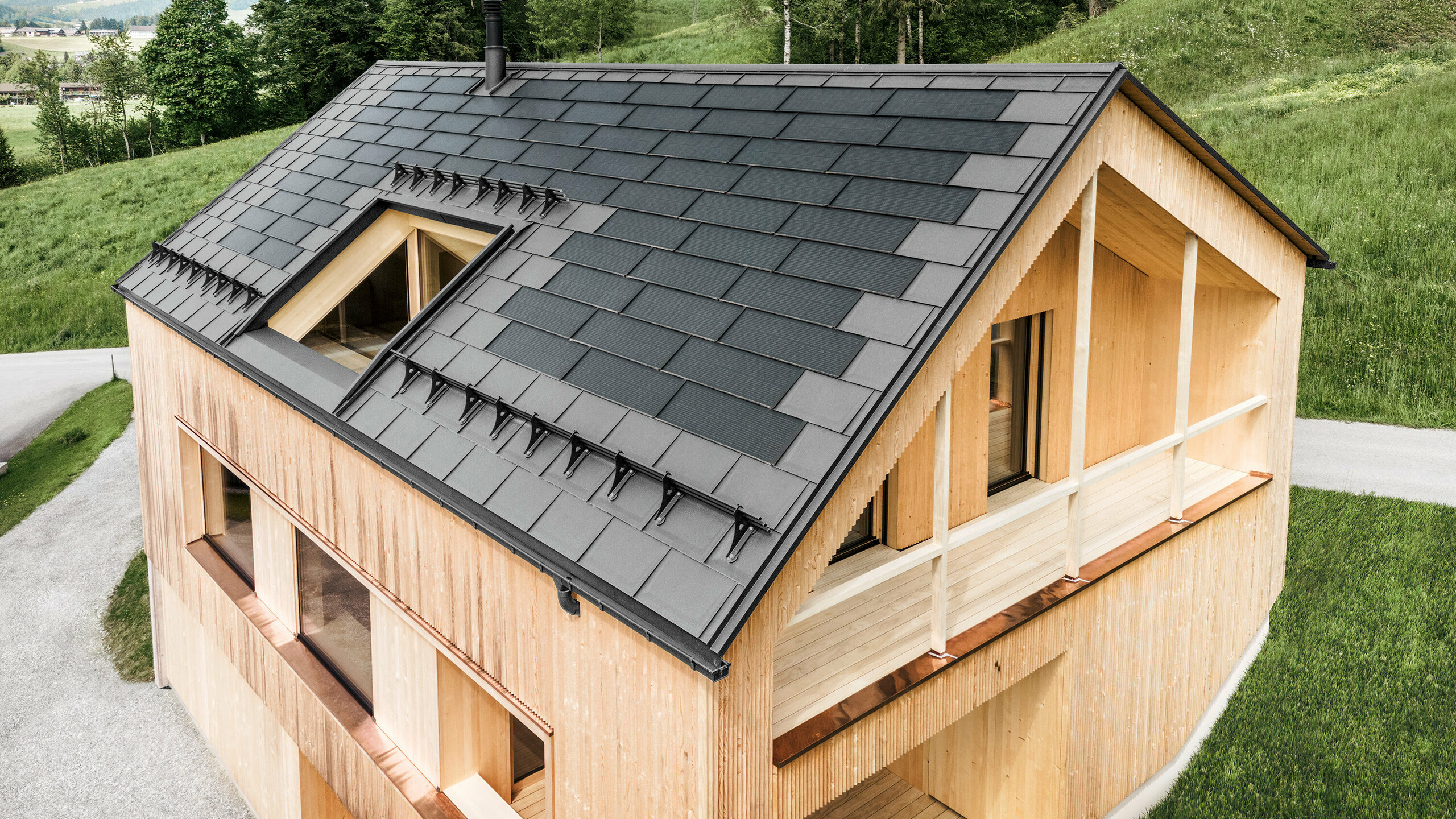 Maison individuelle dans la localité autrichienne d'Egg avec le panneau solaire de toiture PREFA et le panneau de toiture R.16 en gris clair, combinés à une façade en bois