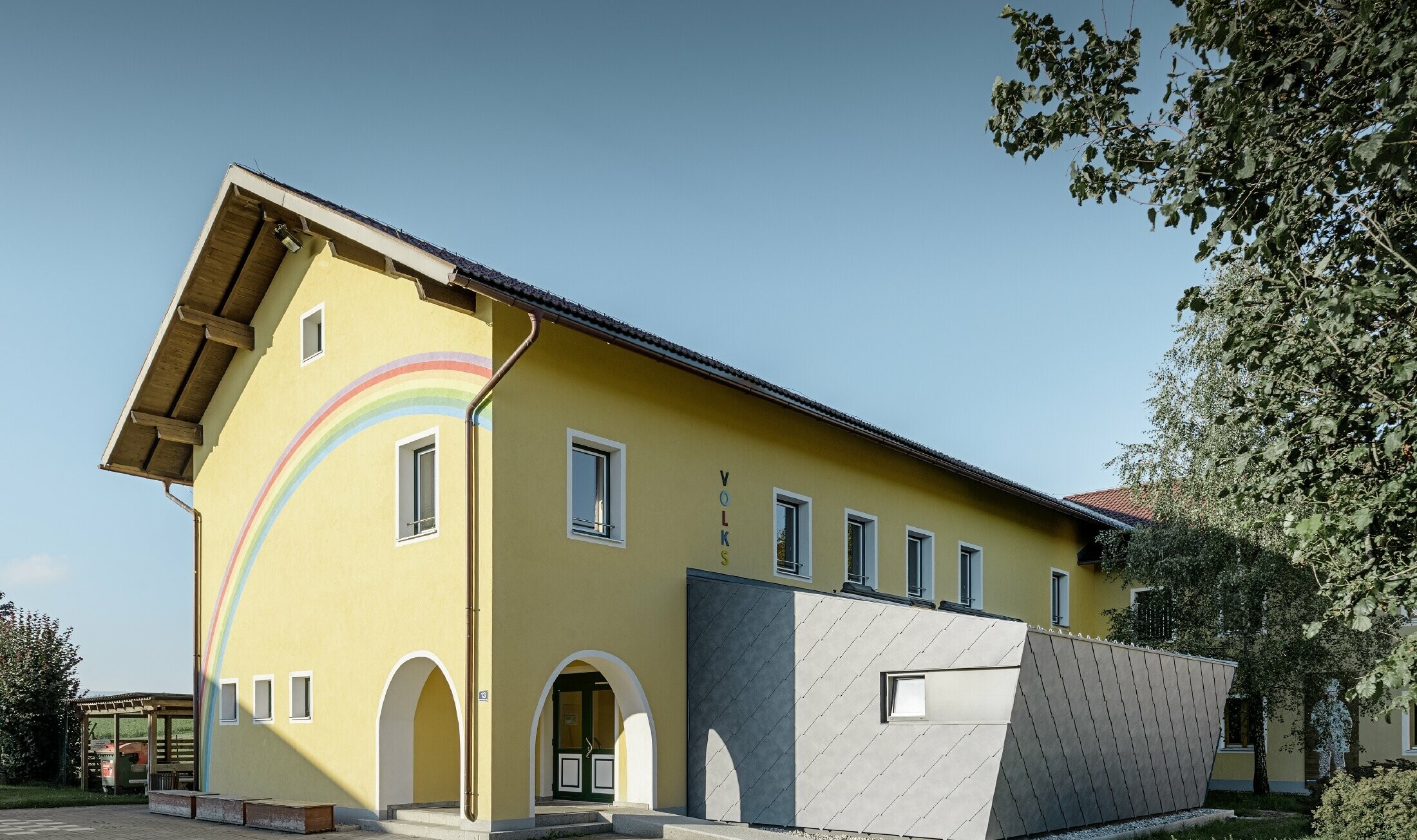 Annexe d’une école primaire — Habillée de losanges de toiture et de façade PREFA en aluminium de couleur gris pierre