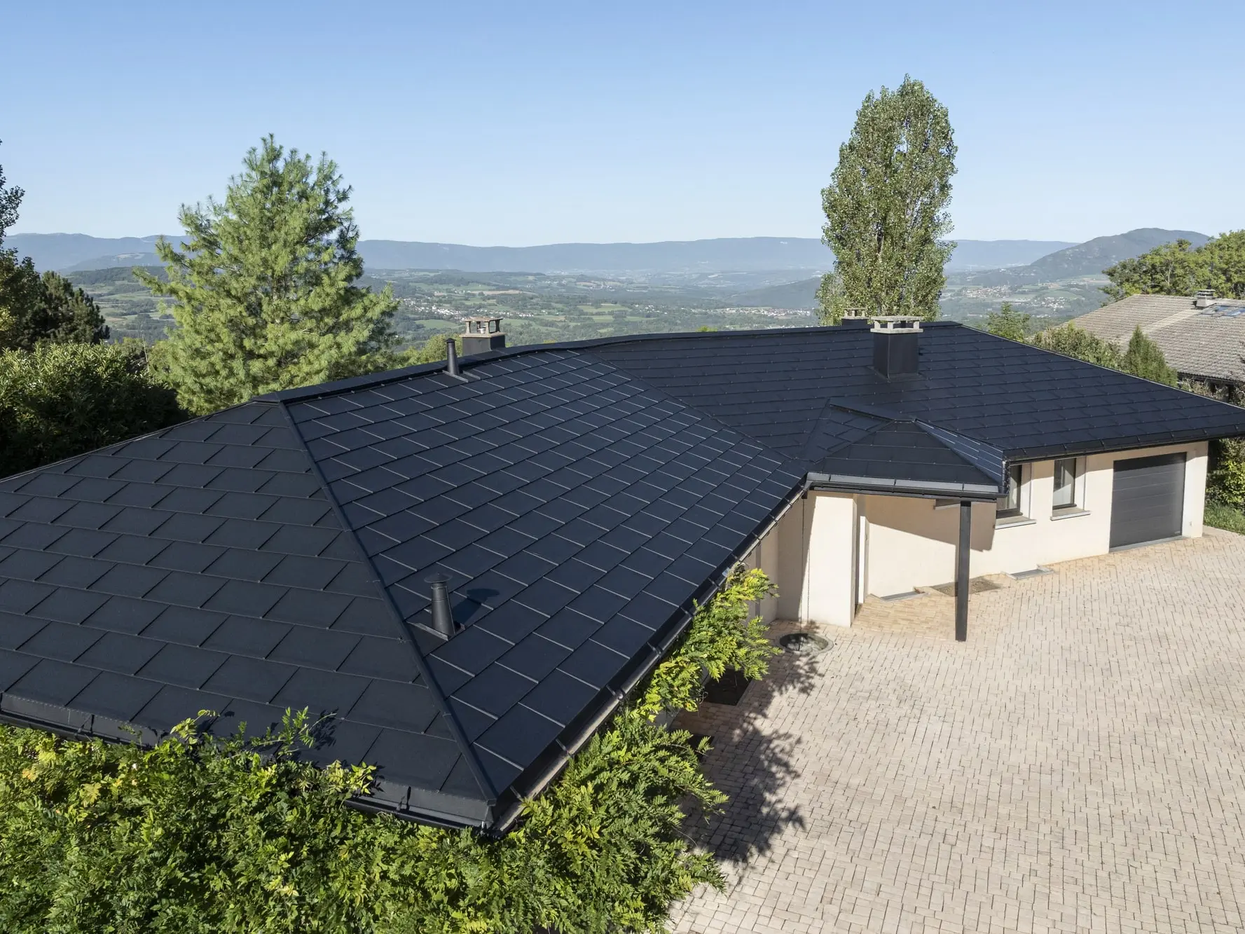 Vue d'ensemble de cette maison individuelle récemment rénovée avec les produits en aluminium PREFA : gouttière demi-ronde, R.16 et joint debout Prefalz en P.10 noir