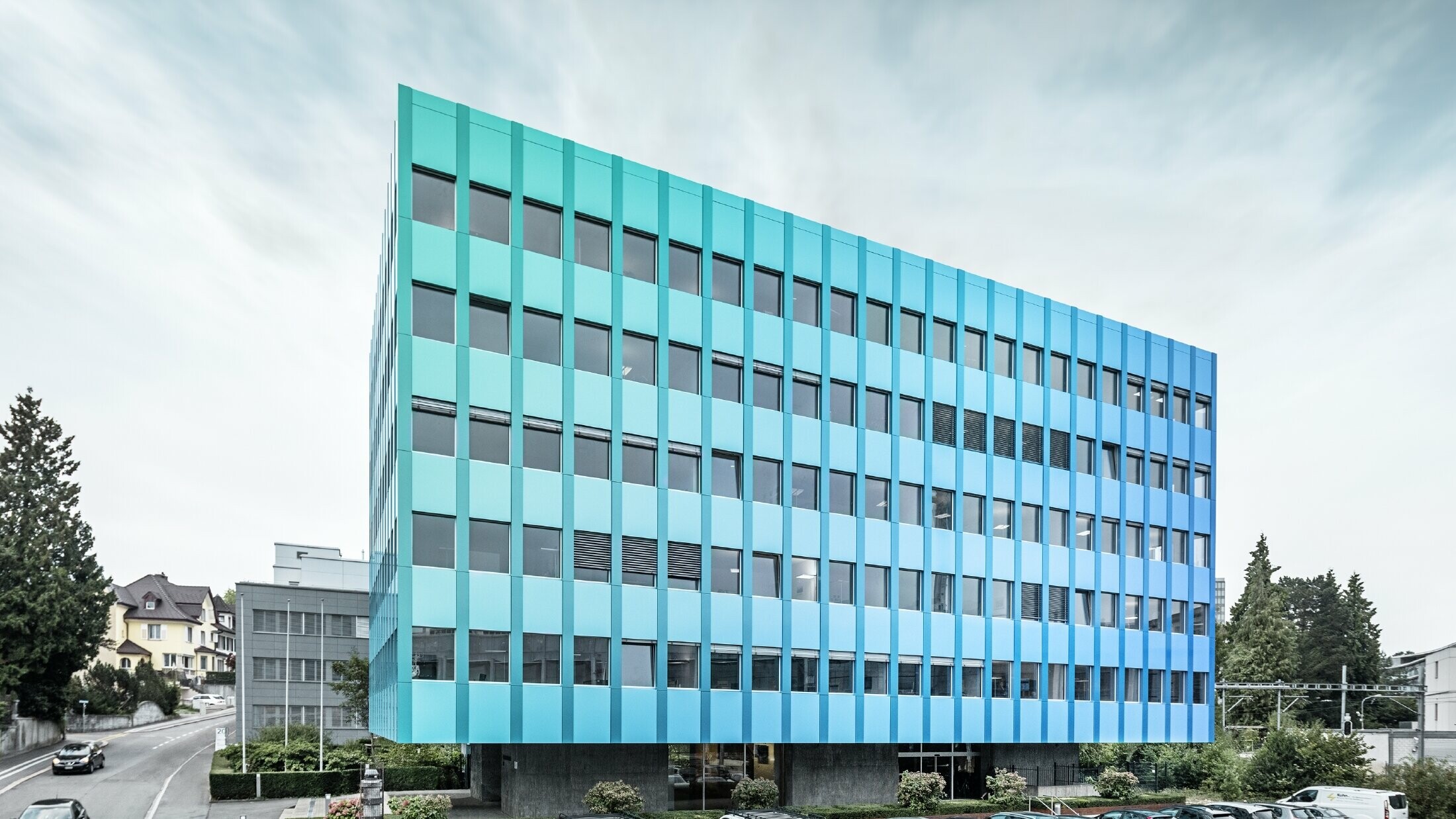 Vue latérale de la maison Wieland à Aarau ; la façade est revêtue de panneaux composites PREFABOND en aluminium de PREFA, qui brillent d'un éclat bleu-vert grâce à un procédé de revêtement spécial.
