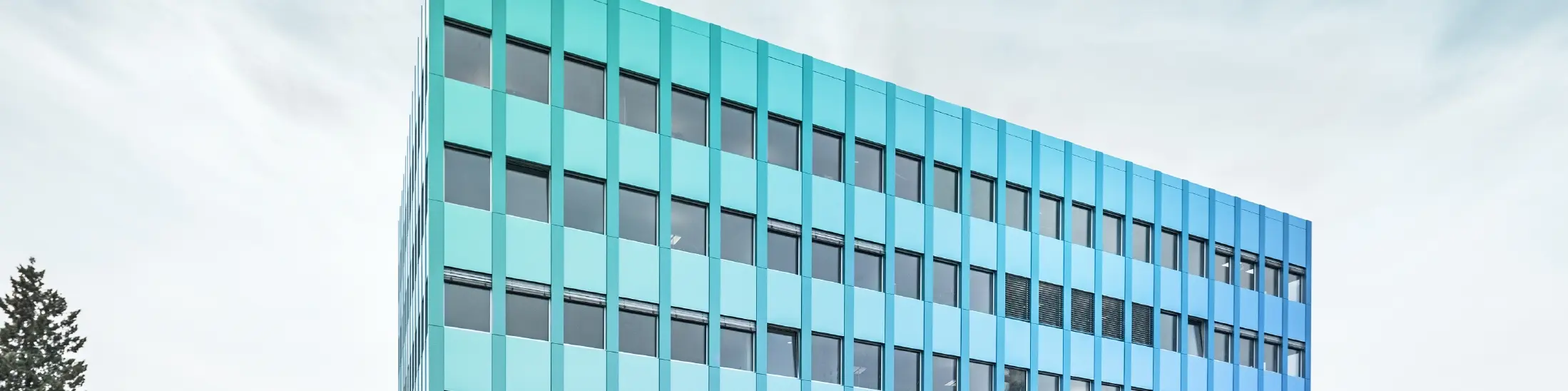Vue latérale de la maison Wieland à Aarau ; la façade est revêtue de panneaux composites PREFABOND en aluminium de PREFA, qui brillent d'un éclat bleu-vert grâce à un procédé de revêtement spécial.