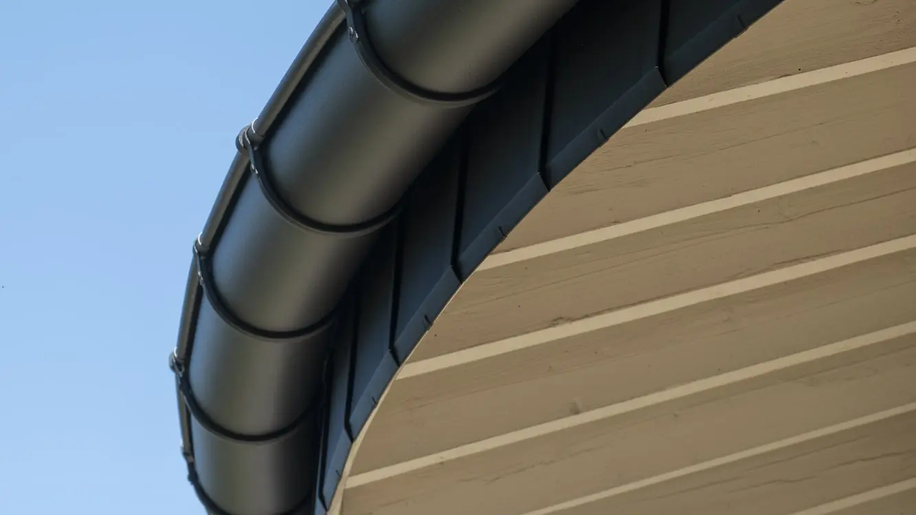Zoom sur la courbe de la toiture avec la sous-face et la gouttière demi-ronde qui épouse parfaitement la forme grâce à la flexibilité des produits en aluminium PREFA