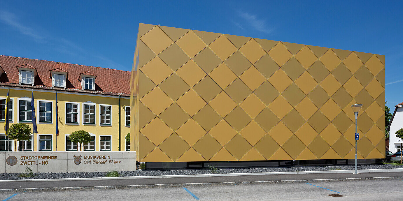 Blick von der Straße auf den Musikverein Zwettl. Das quaderförmige Gebäude ist vollständig mit PREFA Aluminium Verbundplatten umhüllt. 