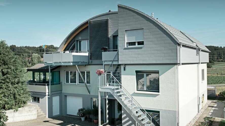 Bâtiment d’habitation avec toit en berceau couvert de tuiles et Prefalz PREFA couleur P.10 gris souris