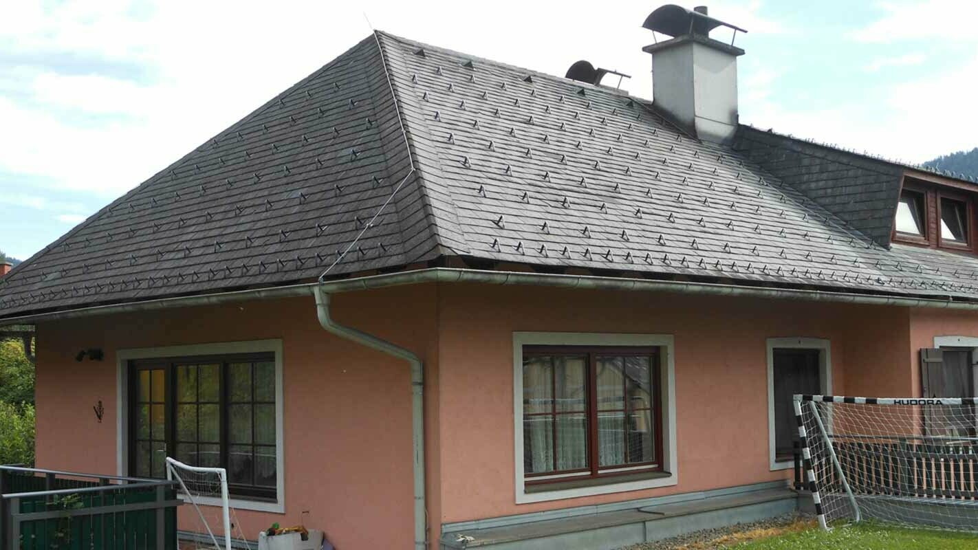 Toit à croupes avant la rénovation de toiture d’une maison avec lucarne en trapèze à l’aide de bardeaux de toiture PREFA