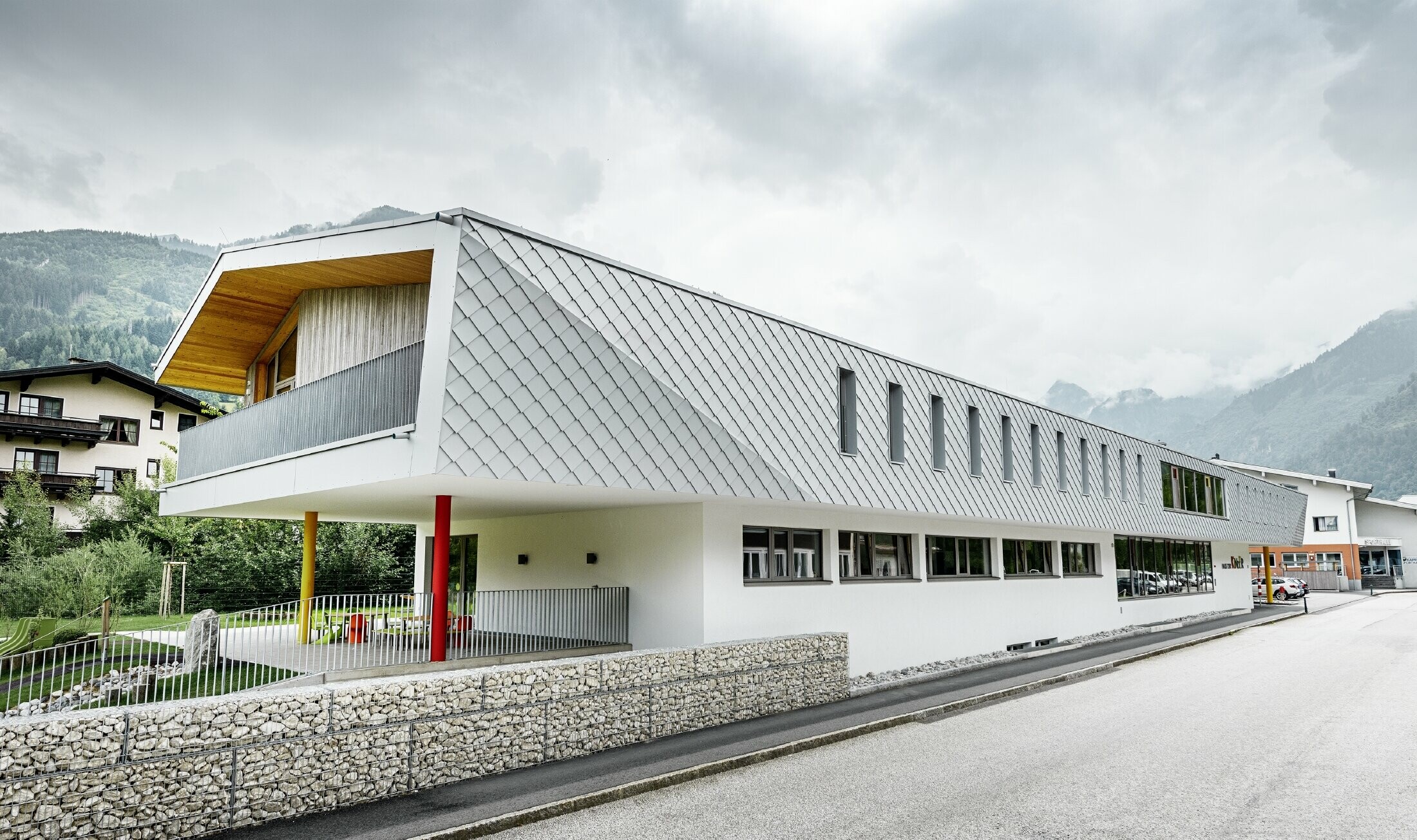 Nouvelle école maternelle de Kaprun — Façade moderne en aluminium réalisée avec des losanges de façade PREFA couleur blanc prefa