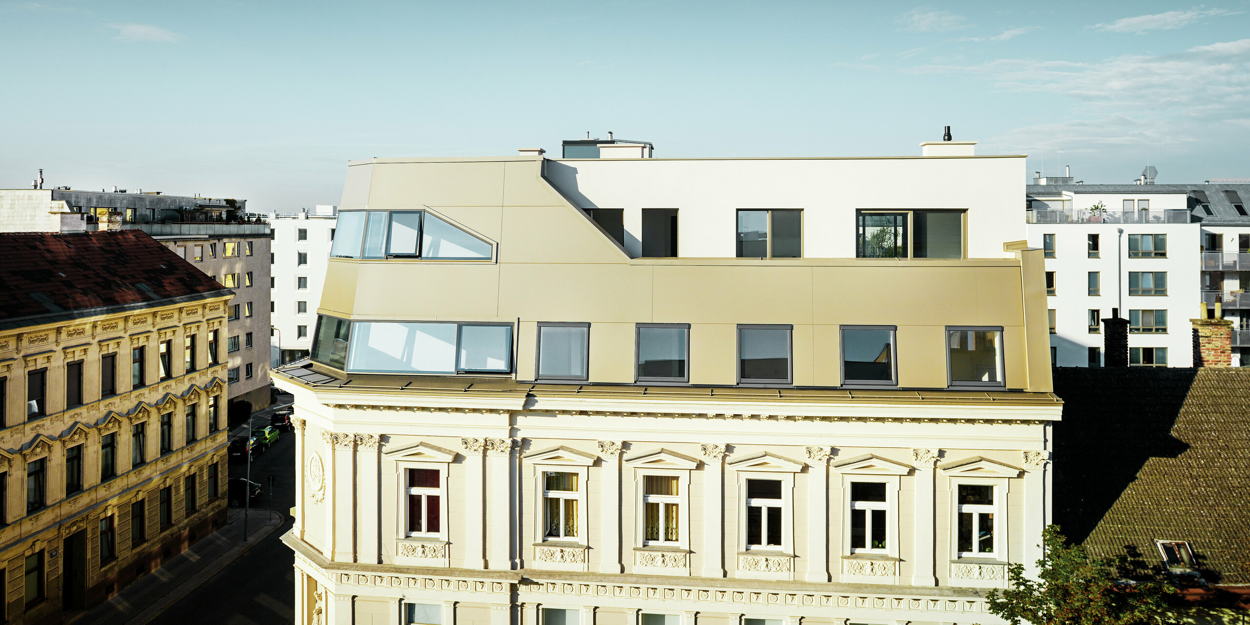 Das neue Dachgeschoss in der Schloßhofer Straße präsentiert sich mit PREFA Aluminium Verbundplatten in Bronze als architektonisch durchdachter Kontrast zum Altbau. Die Kombination aus Funktion, Ästhetik und Langlebigkeit steht für zeitgemäßes städtisches Wohnen. Die klar strukturierten Fensterachsen und die hochwertige Aluminiumfassade schaffen ein durchdachtes Zusammenspiel von Licht, Fläche und Funktionalität.