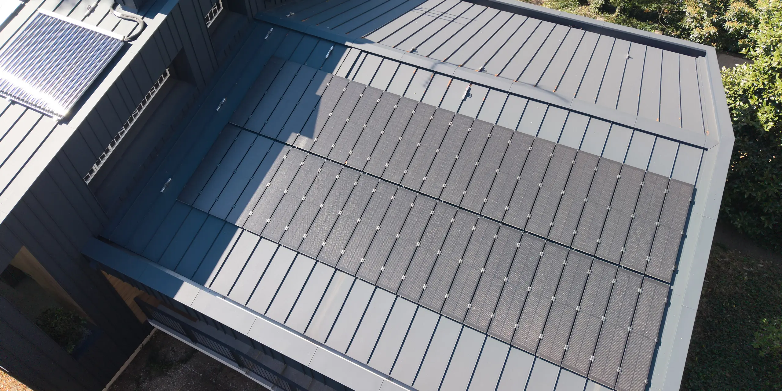 Détail de la toiture en aluminium PREFALZ de la Villa Castellanza, couleur Anthracite, avec ses élégants modules solaires PREFALZ. Cette solution solaire à grande échelle s'intègre harmonieusement au paysage urbain moderne et allie une architecture sophistiquée à une production d'énergie durable. L'aluminium PREFALZ séduit par sa robustesse, sa résistance aux intempéries et son esthétique harmonieuse.
