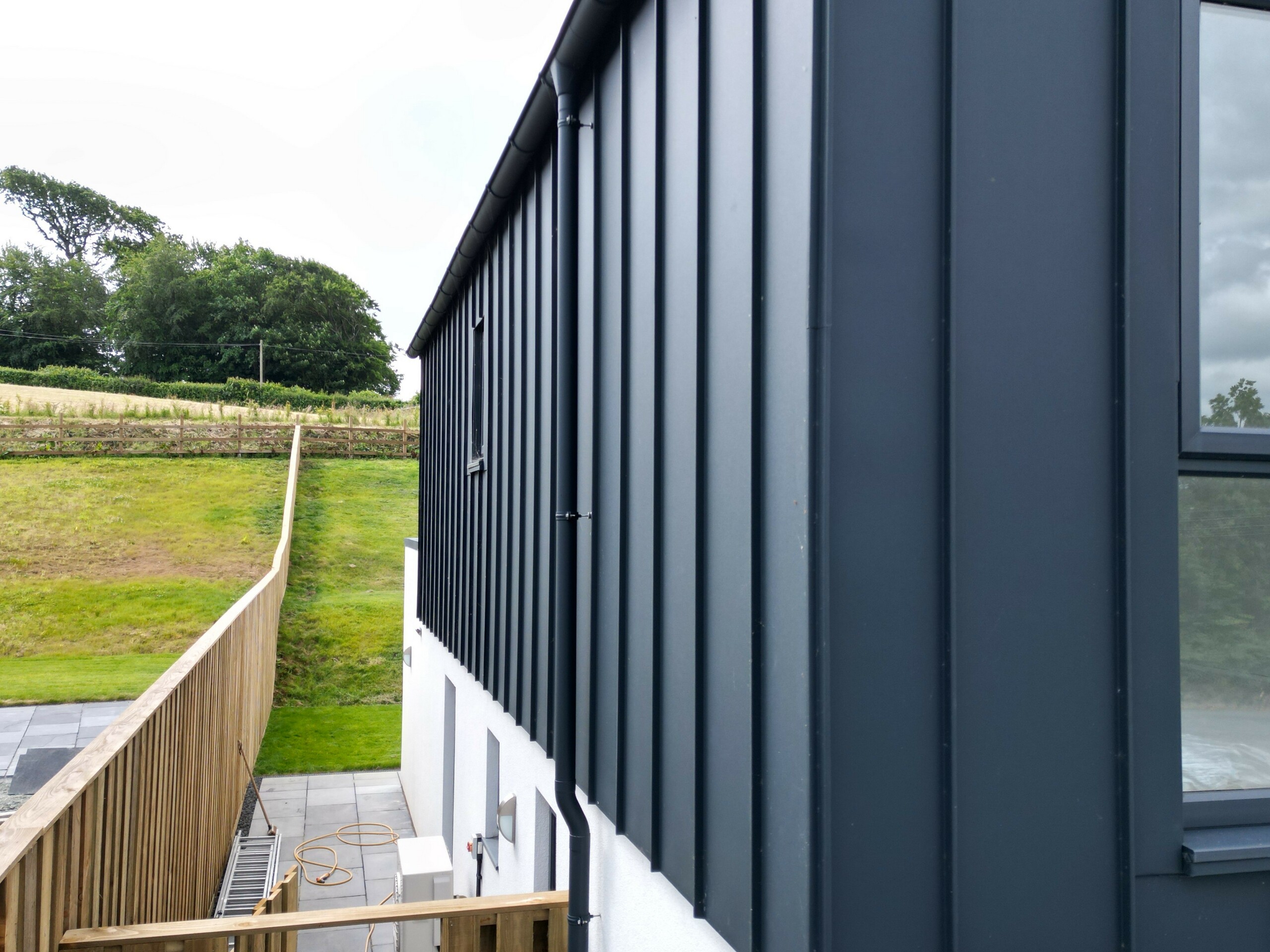 Gros plan de la façade PREFALZ en P.10 anthracite, qui met en valeur l'aluminium de haute qualité et la finition précise de la toiture à joint debout. Les lignes claires et la surface résistante aux UV font de cette façade un accroche-regard moderne.