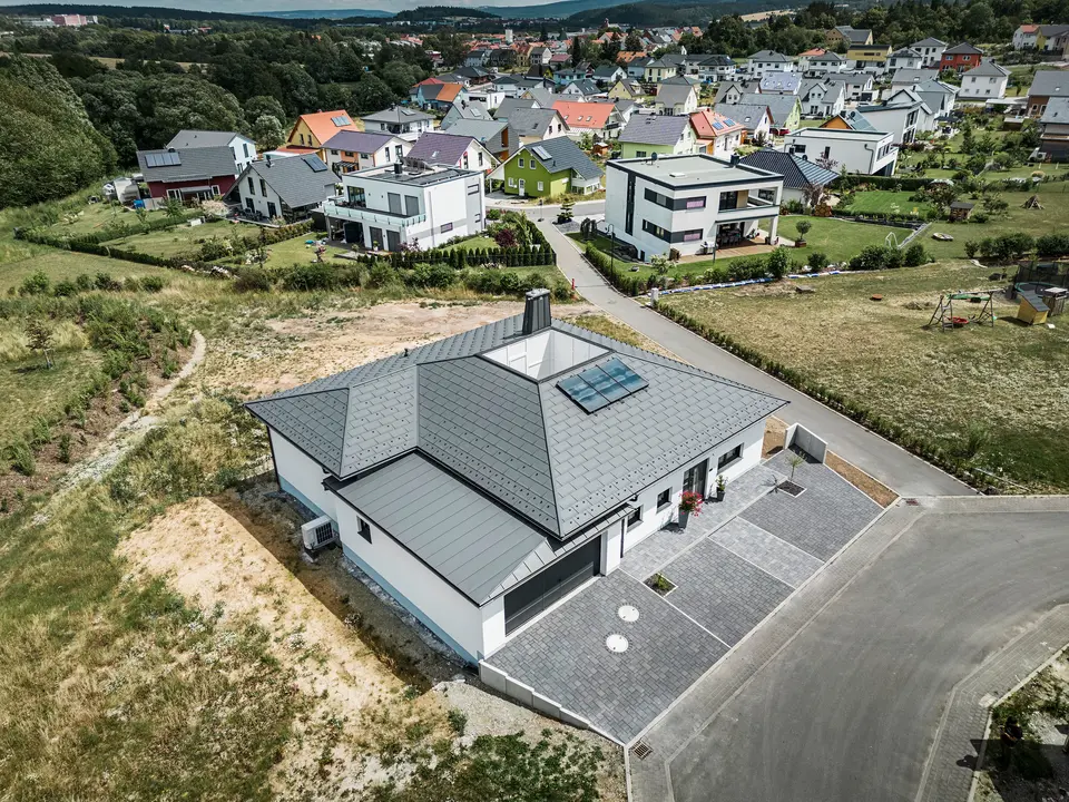 R.16 PREFA et joint debout PREFALZ ainsi que tuyau de descente et gouttière suspendue en P.10 gris sombre sur le toit d'un bungalow. 