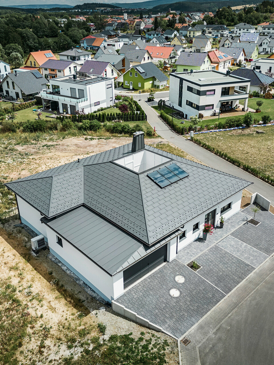 R.16 PREFA et joint debout PREFALZ ainsi que tuyau de descente et gouttière suspendue en P.10 gris sombre sur le toit d'un bungalow. 