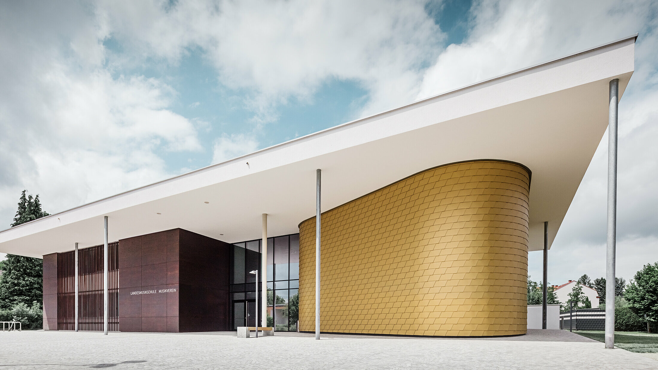 Des bardeaux en aluminium dorés de PREFA ornent la façade arrondie de l’école de musique