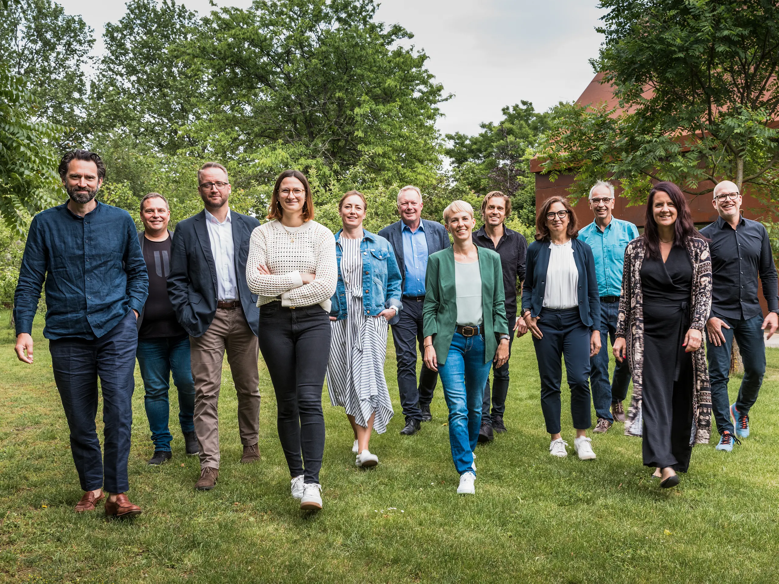 Groupe d’experts et d’architectes lors du dialogue PREFARENZEN 2025 : Le jury, composé de dix architectes et experts PREFA, avance à l’unisson sur une pelouse verdoyante devant la Résidence Velich, dans le Seewinkel au Burgenland. Ils sourient et se dirigent droit vers l’objectif. À l’arrière-plan, la luxuriante végétation environnante se dévoile. Cette photo a été prise avant que le jury ne sélectionne les projets architecturaux les plus captivants pour la plateforme d’architecture PREFA 2025. Lors du dialogue PREFARENZEN de mai 2024, l’accent a été mis sur la fonctionnalité, la simplicité et la valeur ajoutée des projets architecturaux contemporains. Sur l’image, de gauche à droite : Thomas Heil (co-fondateur, dreiplus Architekten), Jürgen Haller (bâtisseur, Jürgen Haller GmbH), Christian Wirth (responsable du conseil en bâtiment, PREFA Autriche), Chiara Desbordes (responsable du contenu, Architektur aktuell), Paulina Frey (directrice marketing, PREFA Suisse), Gerald Krebs (conseiller en bâtiment, PREFA Autriche), Veronika Roll (marketing, PREFA Autriche), Daniel Luckeneder (architecte associé, laac zt gmbh), Patricia Ezcurra (architecte, wwa Architekten), Wolfgang Croce (Croce & Wir, Graz), Bettina Almeida (responsable communication, PREFA) et Jürgen Jungmair (directeur marketing international, PREFA).