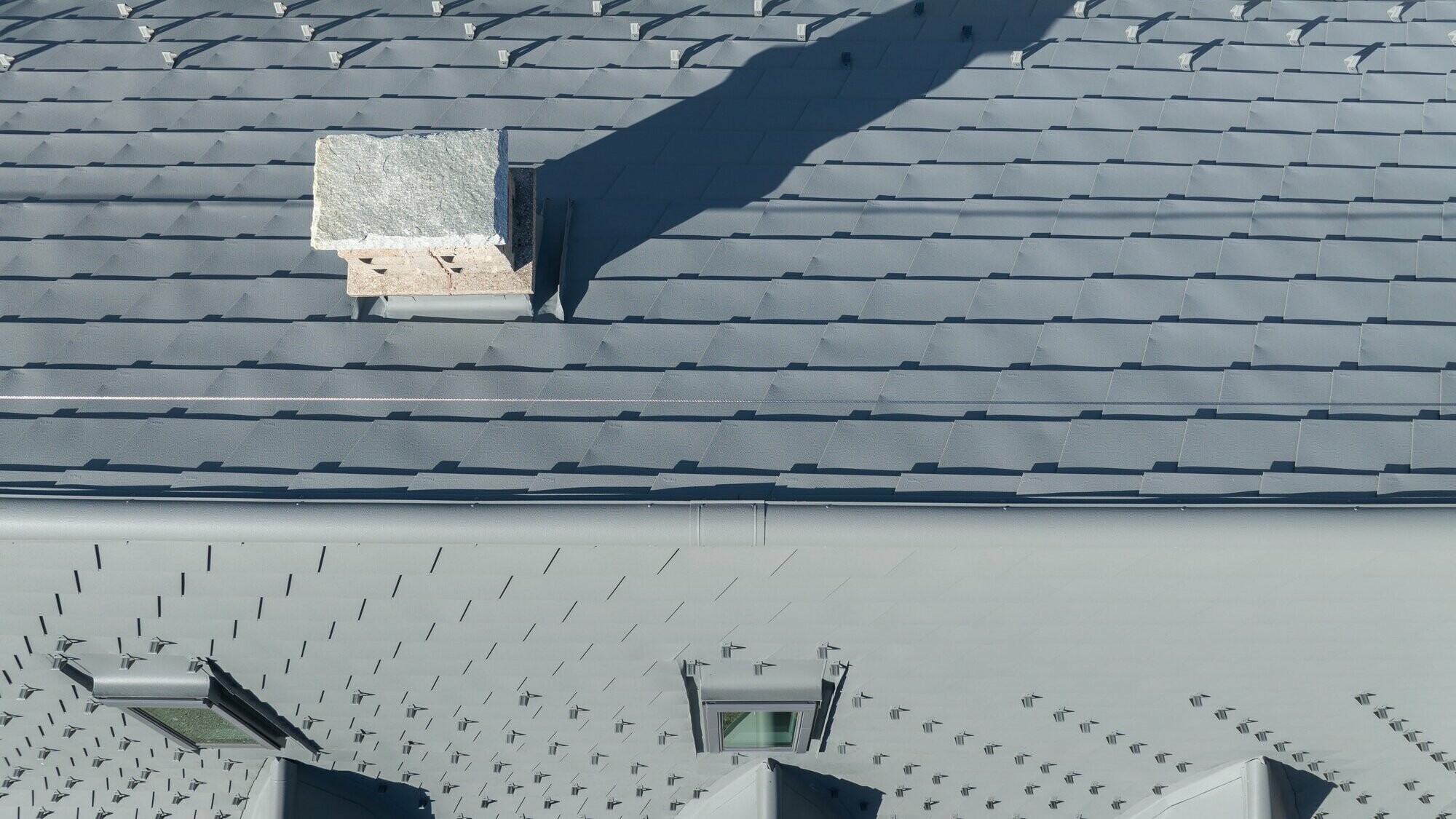 Vue à l'horizontale depuis le ciel de la nouvelle toiture en bardeau PREFA dans la teinte P.10 gris souris stucco