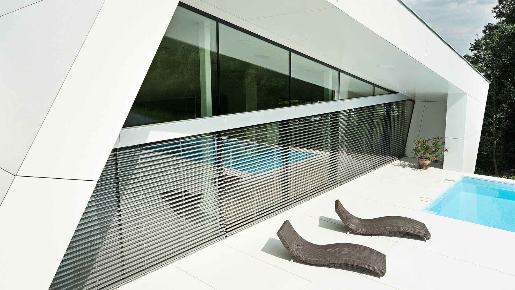 Maison individuelle moderne avec piscine. La façade du bâtiment est recouverte de panneaux composites de couleur blanc pur.