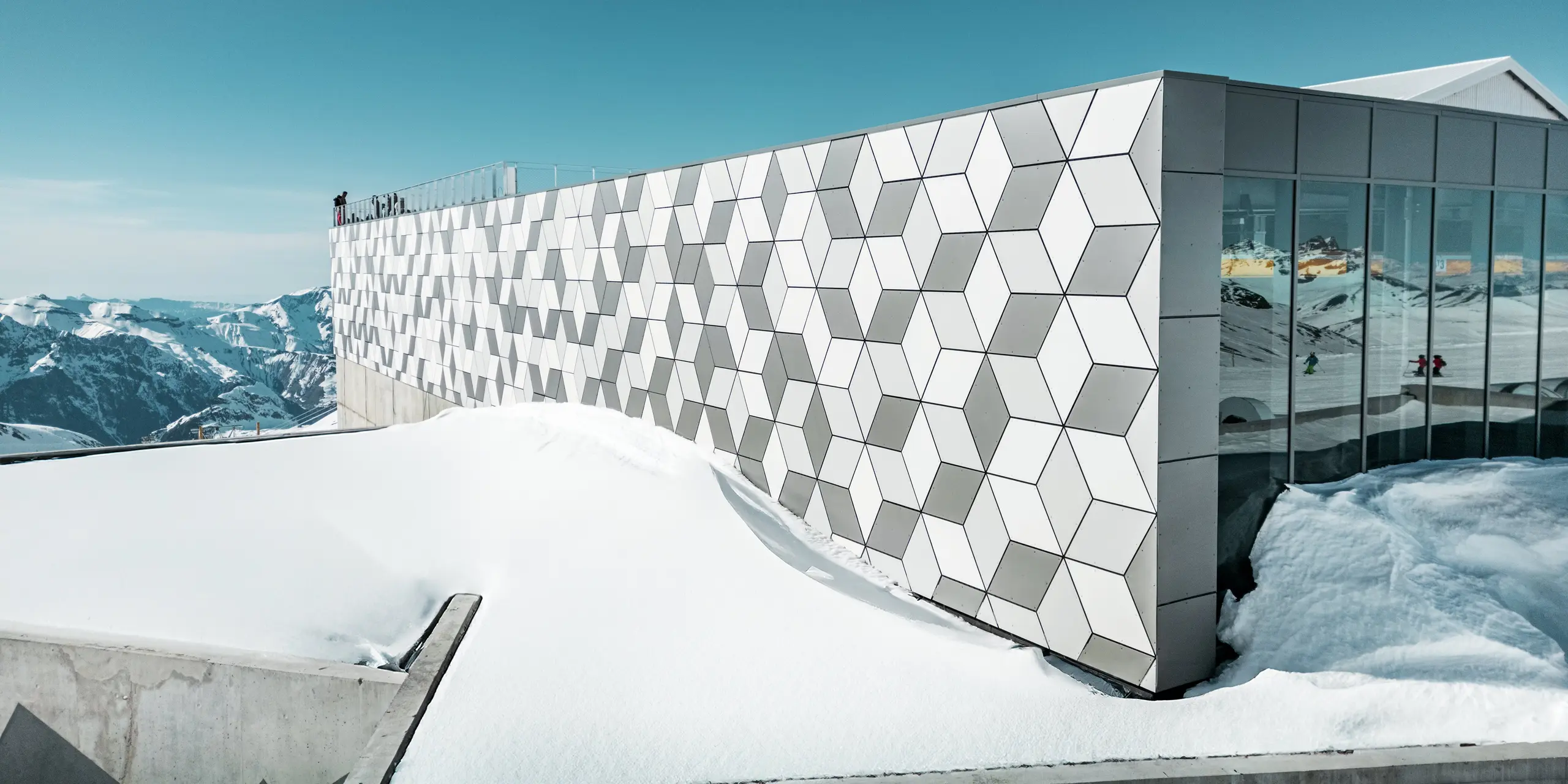 La station supérieure du téléphérique des Deux Alpes arbore une superbe façade en panneaux composites en aluminium PREFABOND disposés en losanges. Les panneaux blancs et gris s'intègrent harmonieusement au paysage montagneux enneigé et reflètent la lumière intense des Alpes. Ce design innovant allie raffinement esthétique et grande résistance aux conditions climatiques extrêmes.