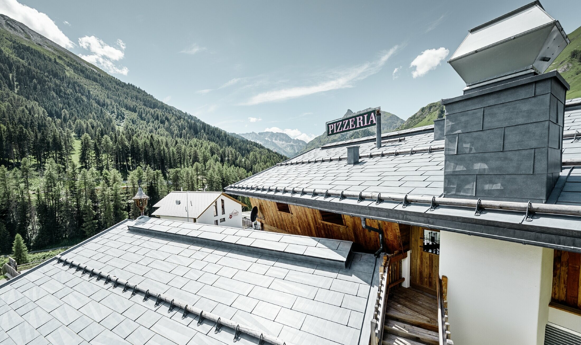 Restaurant Almrausch au cœur d’un décor de montagnes — Toiture PREFA réalisée avec des panneaux de toiture FX.12 gris pierre et dotée de tubes pare-neige