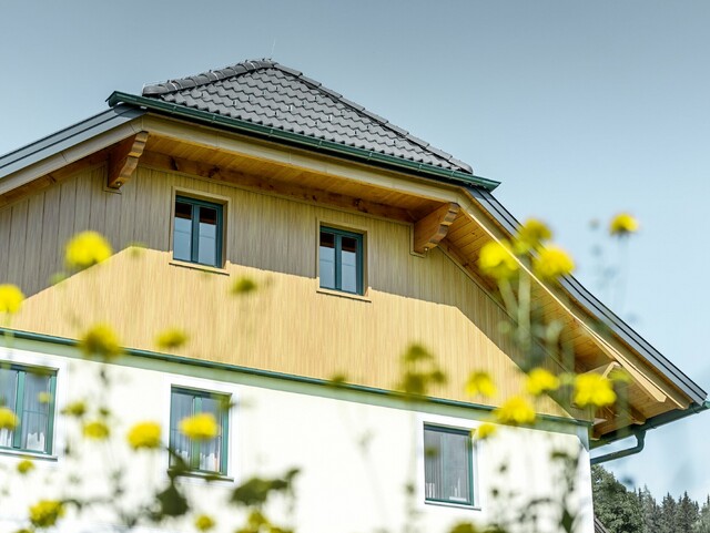Revêtement de pignon avec panneaux en aluminium de PREFA imitation (chêne naturel) ; les Sidings sont posés à la verticale avec revêtement de la sous-face de toiture