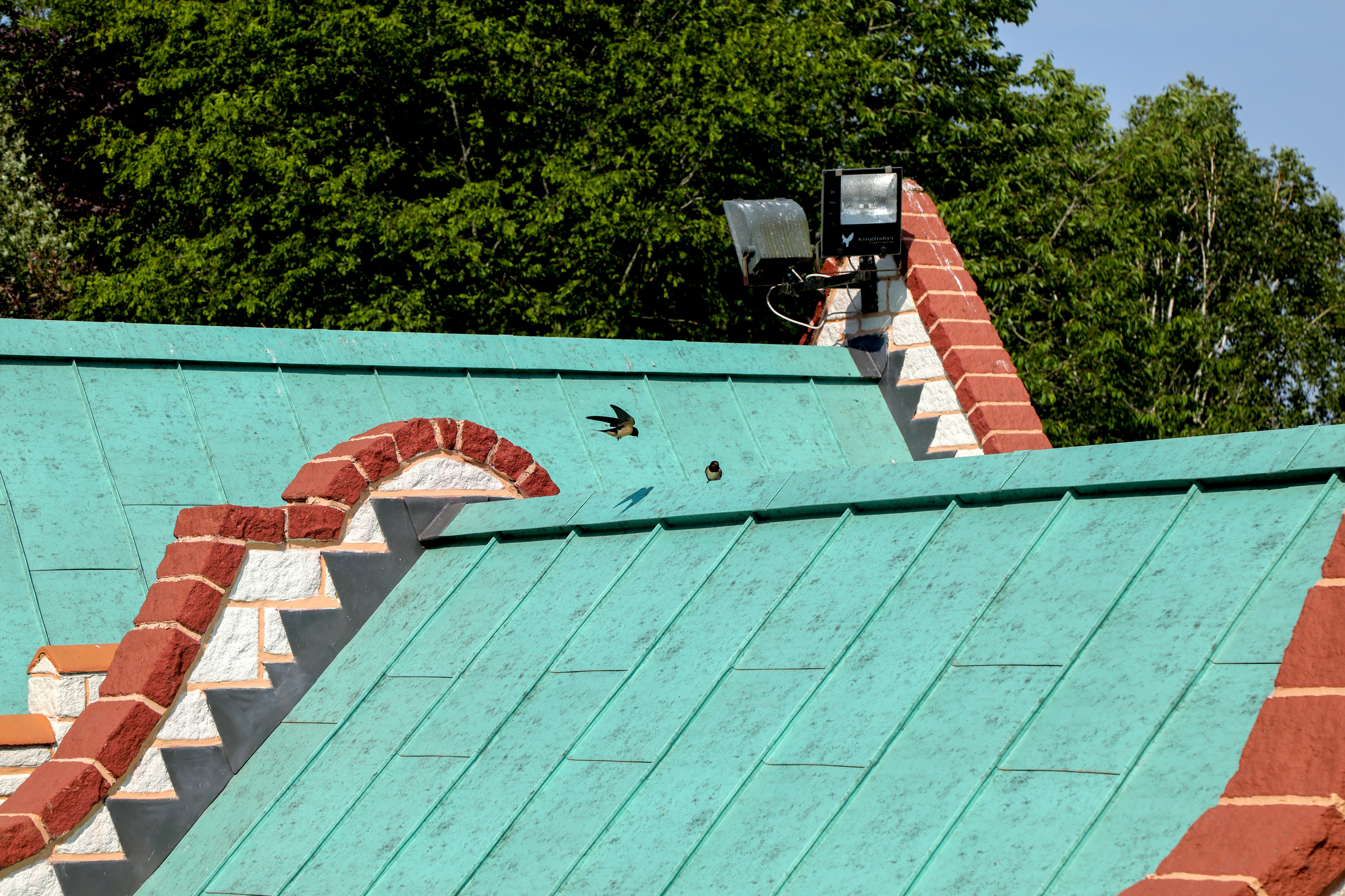 À Sundown Adventureland, la toiture ludique se caractérise par des lignes fluides, des pignons en briques rouges saisissants et des oiseaux en vol qui attirent le regard. La toiture en aluminium PREFALZ, coloris P.10 Vert de gris, crée un fort contraste visuel et souligne l'architecture féerique du château. Les joints debout précis mettent en valeur les formes dynamiques et permettent une exécution impeccable, même pour des géométries complexes. Par ailleurs, la toiture PREFALZ impressionne par sa haute résistance, sa résistance à la corrosion et sa durabilité – idéale pour une architecture sophistiquée et détaillée.